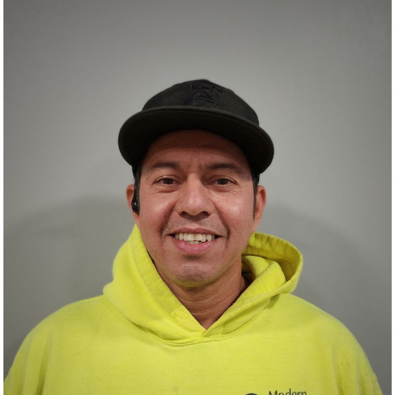 Headshot of man in neon construction sweater and black hat with the word Modern Exterior on it.